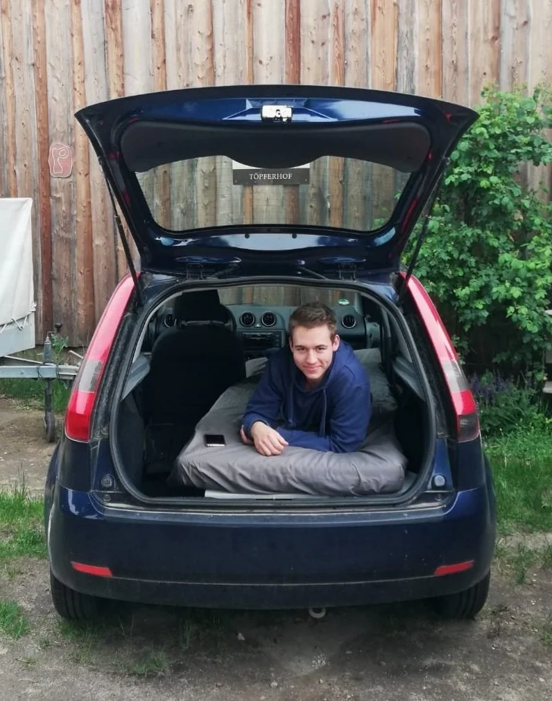 Valentin Rost liegt auf der Matratze seines ersten selbstgebauten Ausbaus im Ford Fiesta